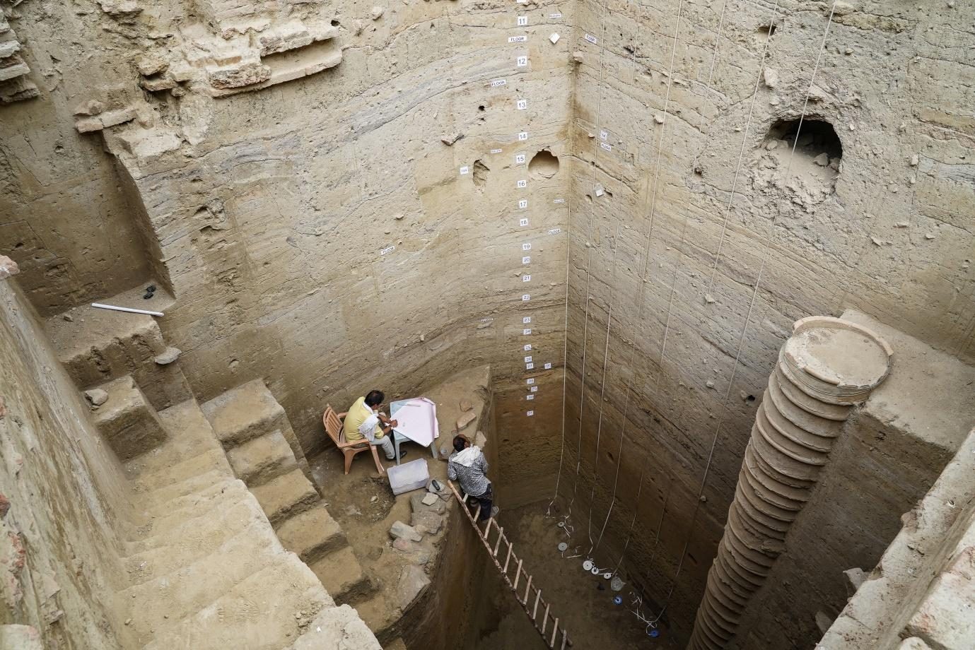 An excavator working at the foot of a very deep trench at Bahaj beside a terracotta ring-well