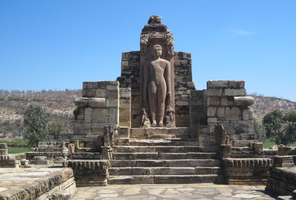 A colossal Jain image beside a temple at Rajorgarh